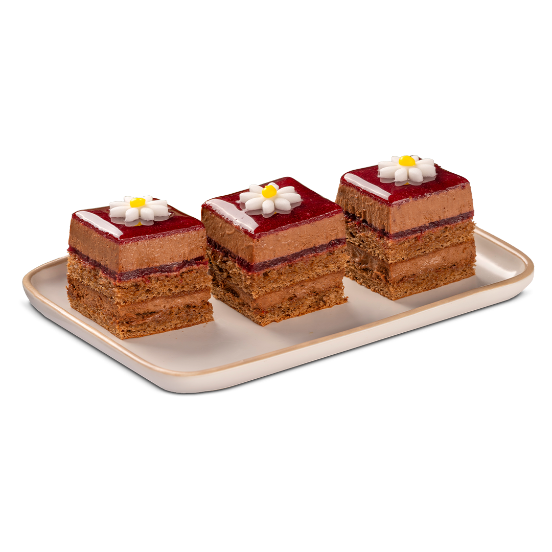 Tres pasteles de chocolate cuadrados en capas, cubiertos con glaseado rojo y flores de azúcar blancas, sobre una band...